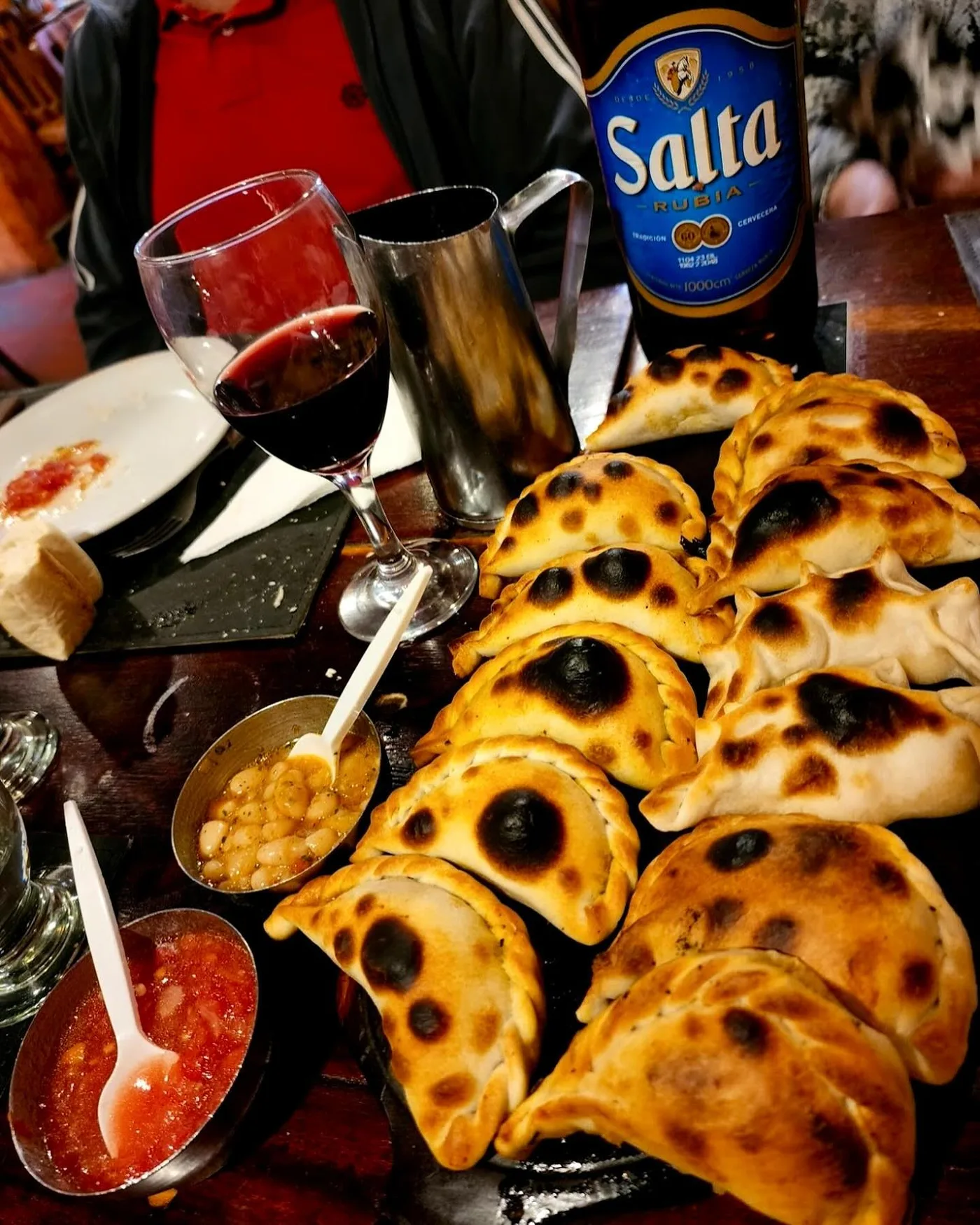 Mesa servida con empanadas, salsas, vino y cerveza Salta