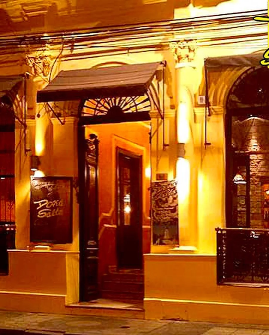 Puerta de entrada de madera de Doña Salta con toldo, de noche